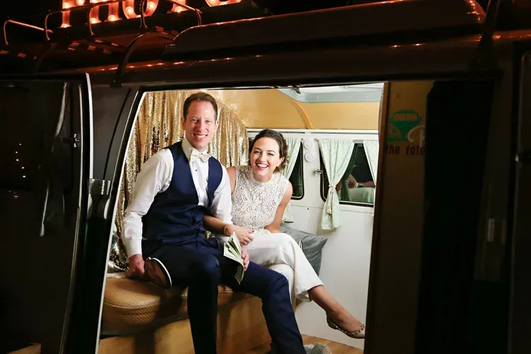 Two people sitting in a vehicle doorway, smiling in a warmly lit interior.