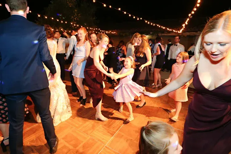 People dancing at a lively indoor party with string lights and wooden floor