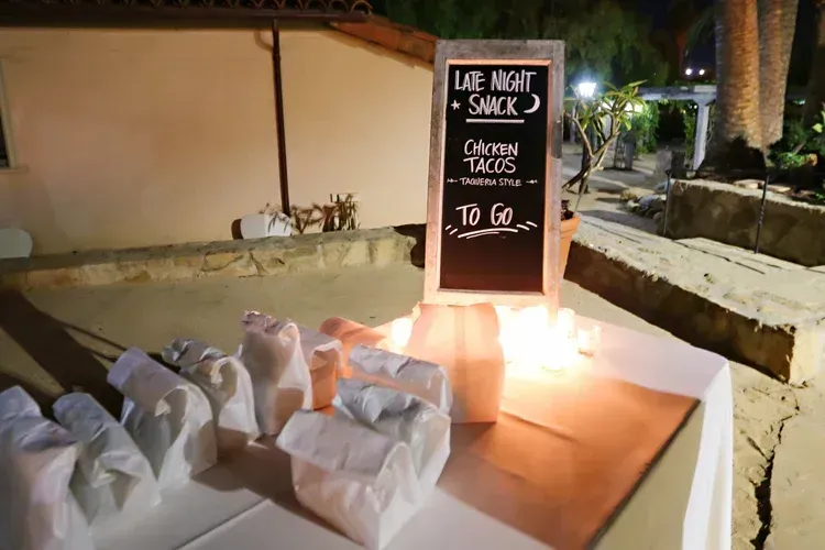 Night market food stall with a chalkboard menu and wrapped items on a table at dusk