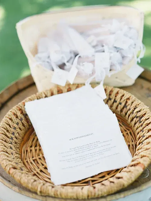 White folded card in a woven basket with tissue paper on a green background