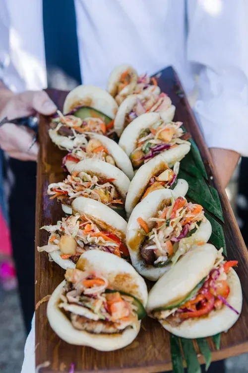 Tray of assorted tacos held by a person in a white shirt