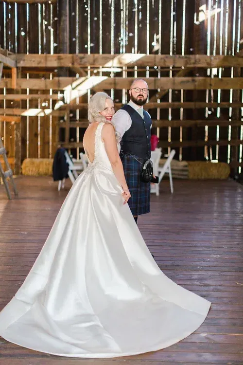 Bride and groom in wedding attire standing in a rustic barn