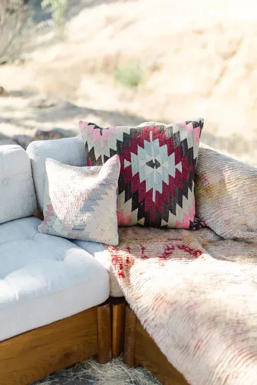 Outdoor sectional sofa with patterned pillows and a fur throw in bright sunlight