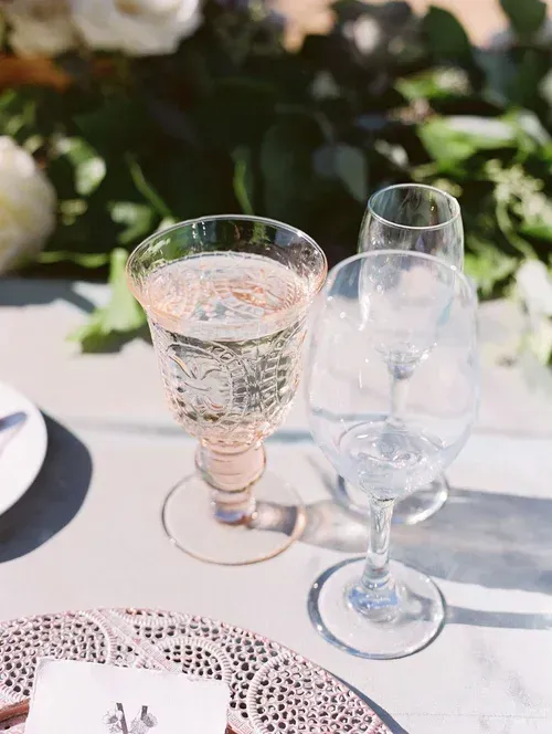 Two clear stemmed glasses on a white table at a formal outdoor setting