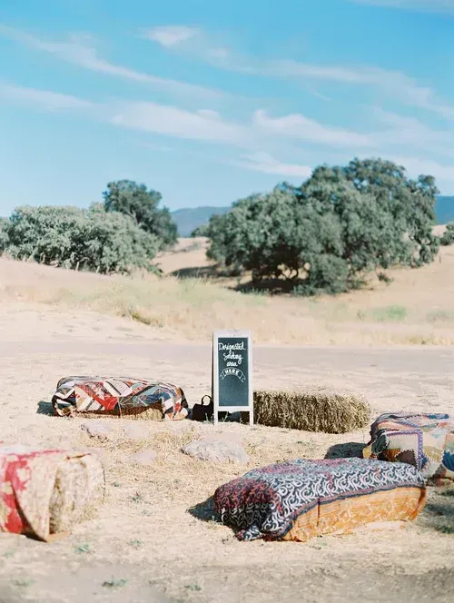 Colorful blankets over low graves in a dry cemetery under a blue sky