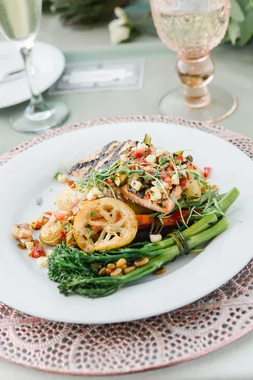 Gourmet fish dish with asparagus and lemon on a white plate at a dining table