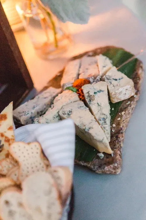 Assorted cheeses on a serving board with crackers and garnishes at a table setting