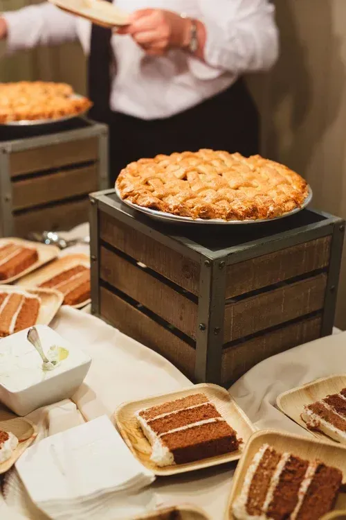 Dessert buffet with pastries on platters and a large tart on a wooden crate display