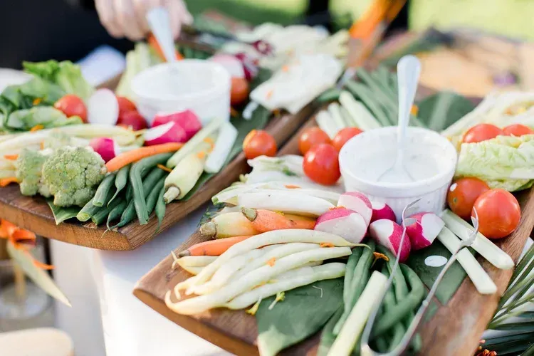 Fresh vegetable platters with dip on wooden boards at a buffet table