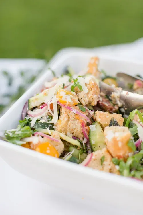 Fresh salad with avocado, orange slices, and red onion in a white bowl outdoors
