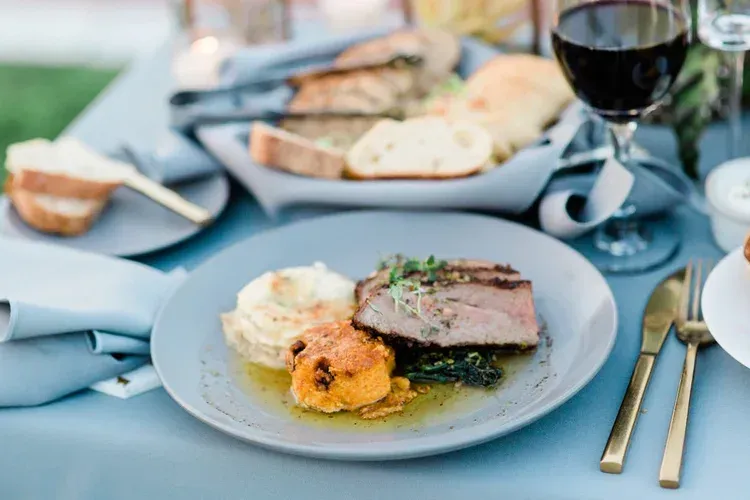 Elegant table setting with plated gourmet meal, bread, and wine glass in a soft blue dining scene