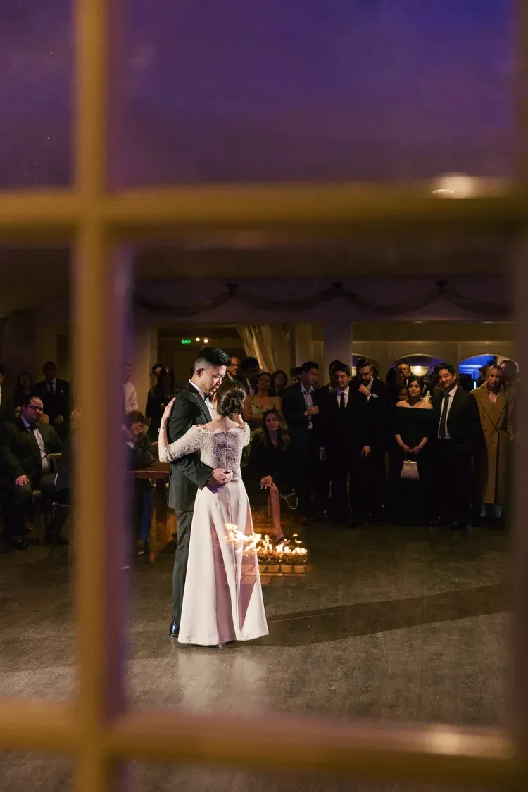 Person in a white dress holding a sparkler at a dimly lit indoor event with a crowd in the background