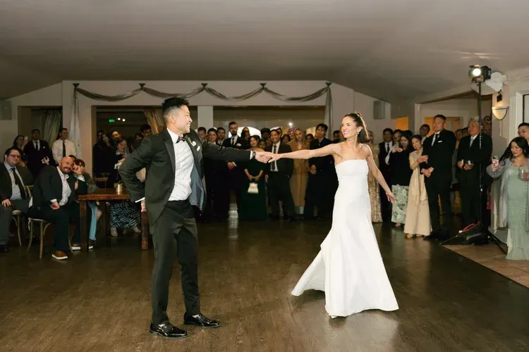 Bride and groom dancing hand in hand at a wedding reception in a decorated hall