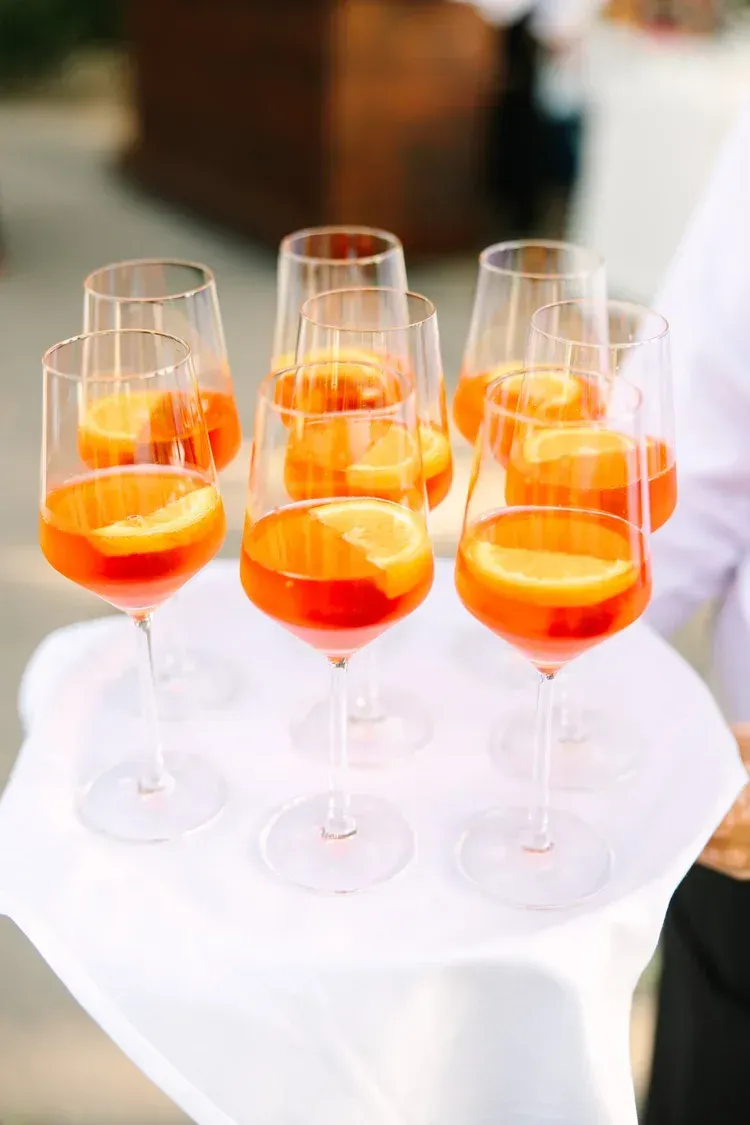 Orange cocktails in champagne flutes arranged on a white tablecloth outdoors