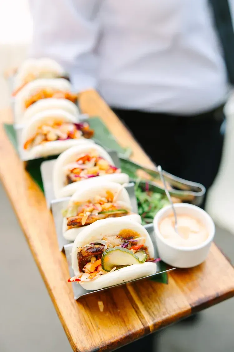 Tray of soft tacos with dipping sauce at a catered event