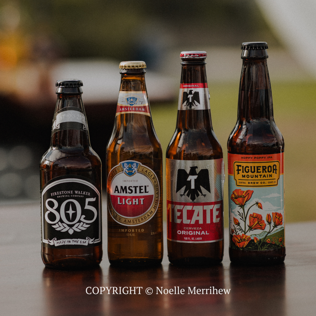 Four bottled beers on a table, including 805, Amstel Light, Tecate, and Figueroa Mountain labels.