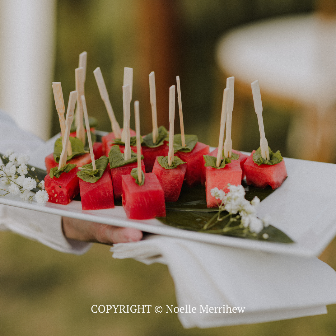 Watermelon appetizer bites with mint and toothpick skewers on a white serving tray
