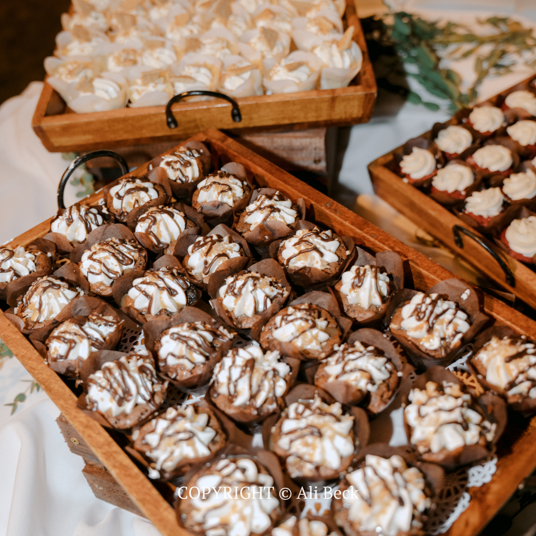 Assorted chocolate truffles in wooden trays, topped with white drizzle on a table