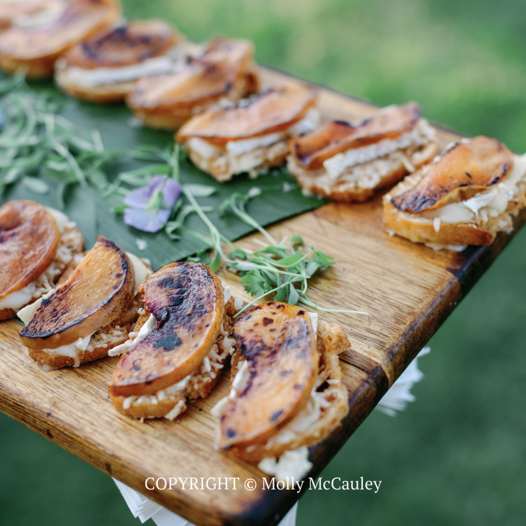 Grilled sandwich wedges on a wooden board with greens and purple flowers