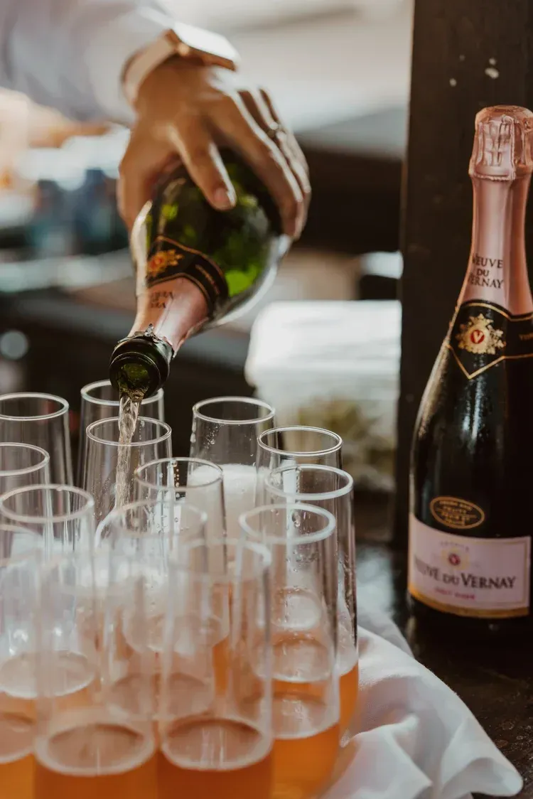 Champagne being poured into flutes beside a bottle on a table
