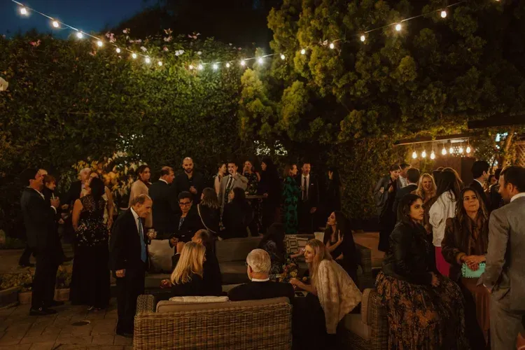 People gathered at a nighttime outdoor party under string lights and trees