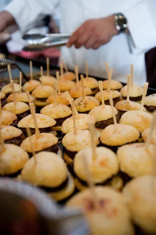 Mini cupcakes on a tray being served with tongs at a buffet