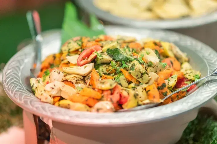 Bowl of colorful pasta salad with shrimp, herbs, and cherry tomatoes, served on a table