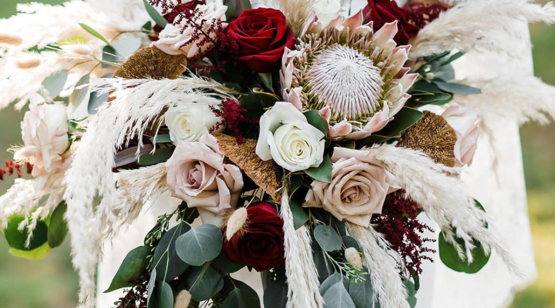 Elegant white, cream, and deep red floral arrangement with greenery and feathery accents