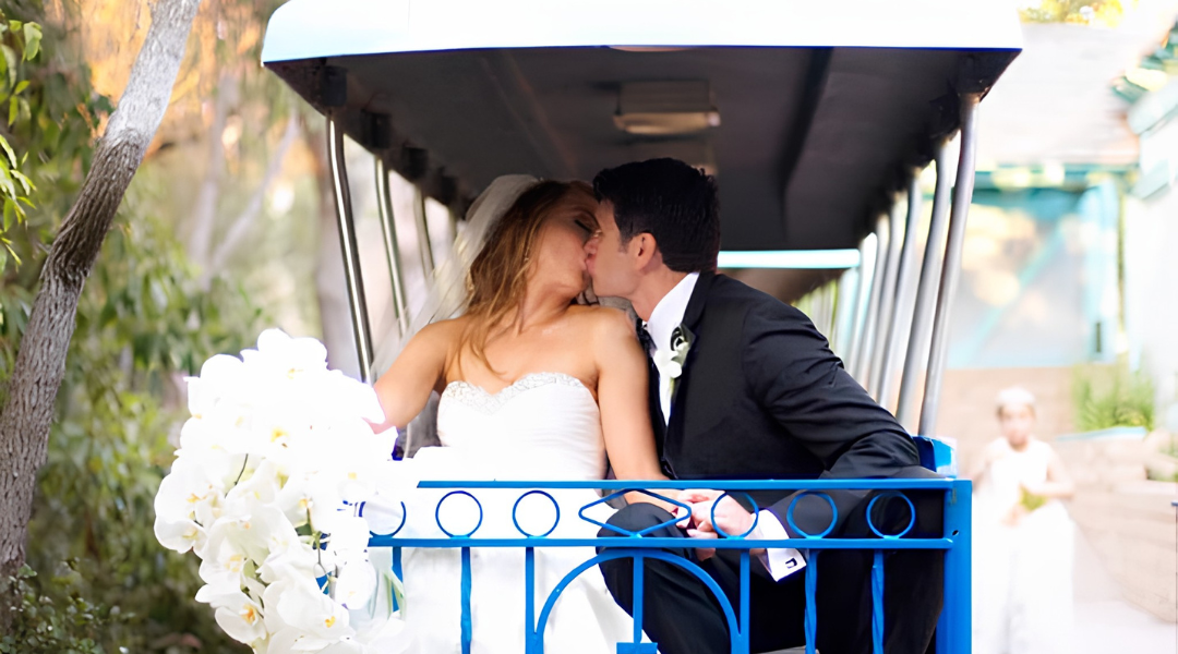 Couple kissing in a flowered golf cart, with a white bouquet in the foreground.