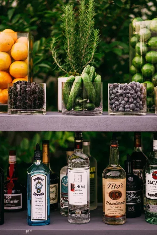 Assorted fruit and liquor bottles displayed on shelves in a colorful market or bar setting