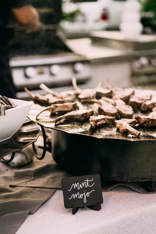 Assorted grilled shrimp on a buffet tray with a small mint garnish sign.