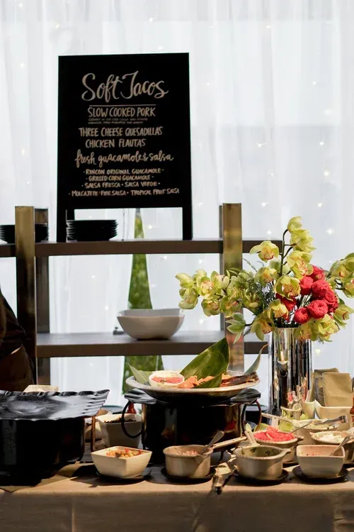 Dessert buffet with bowls, flowers, and a chalkboard sign at a wedding reception