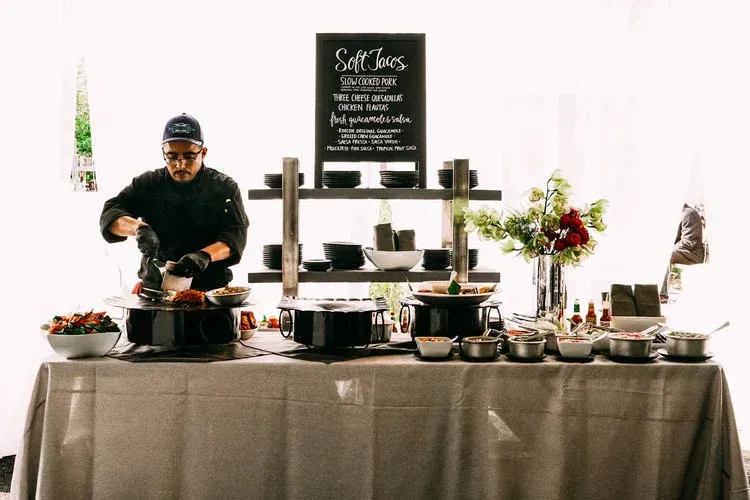 Buffet table with a server arranging food and drinks in a bright event space