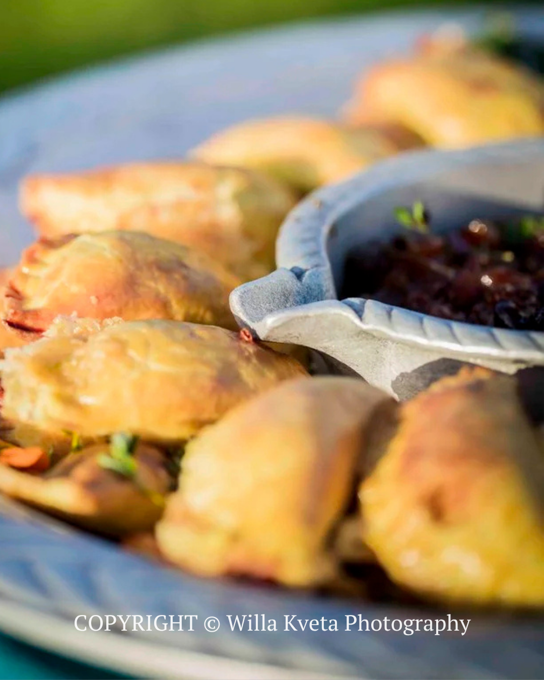 Tray of golden baked pastries with a small bowl of dark dipping sauce