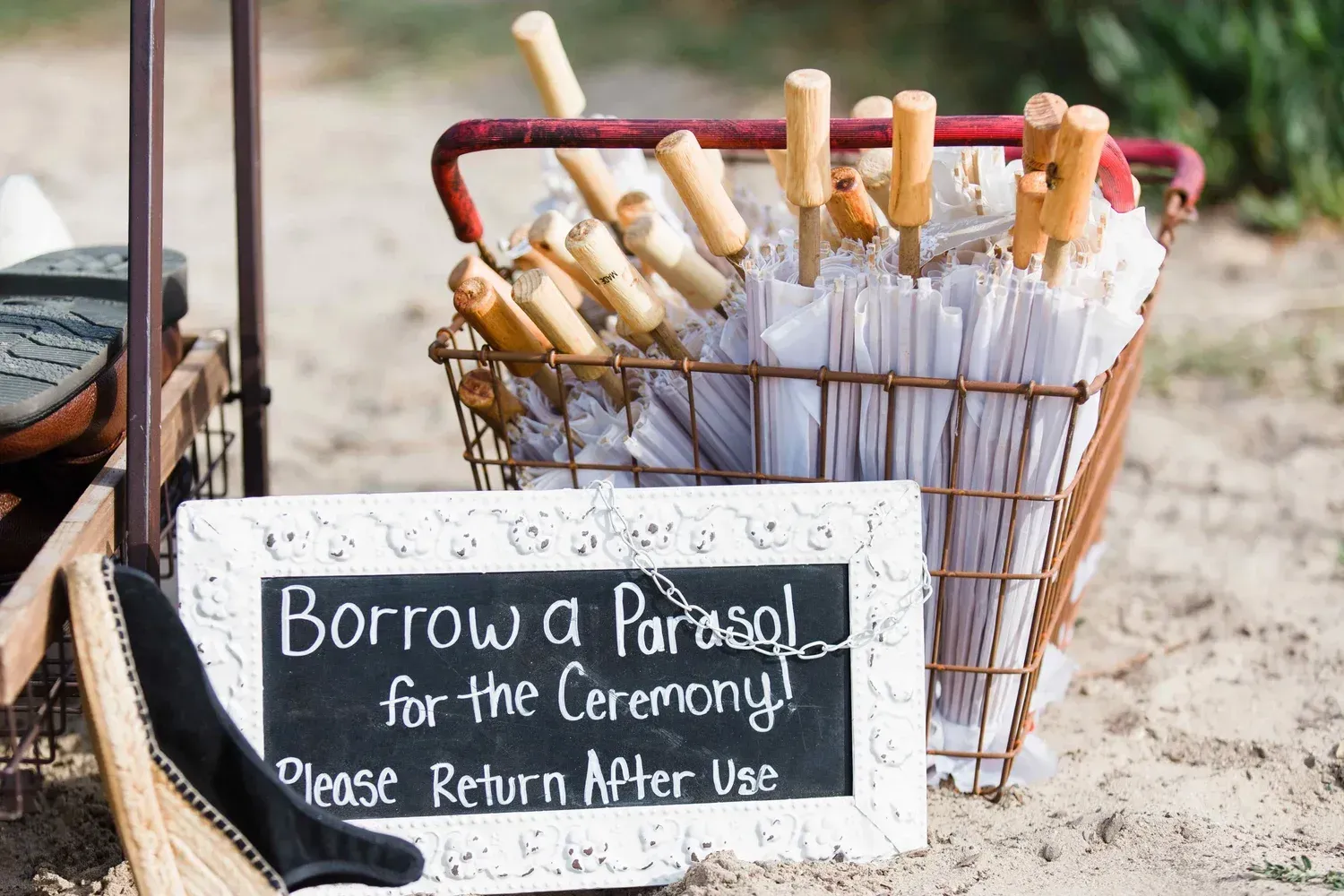 Sign offering parasols for a ceremony, with umbrellas in a basket nearby