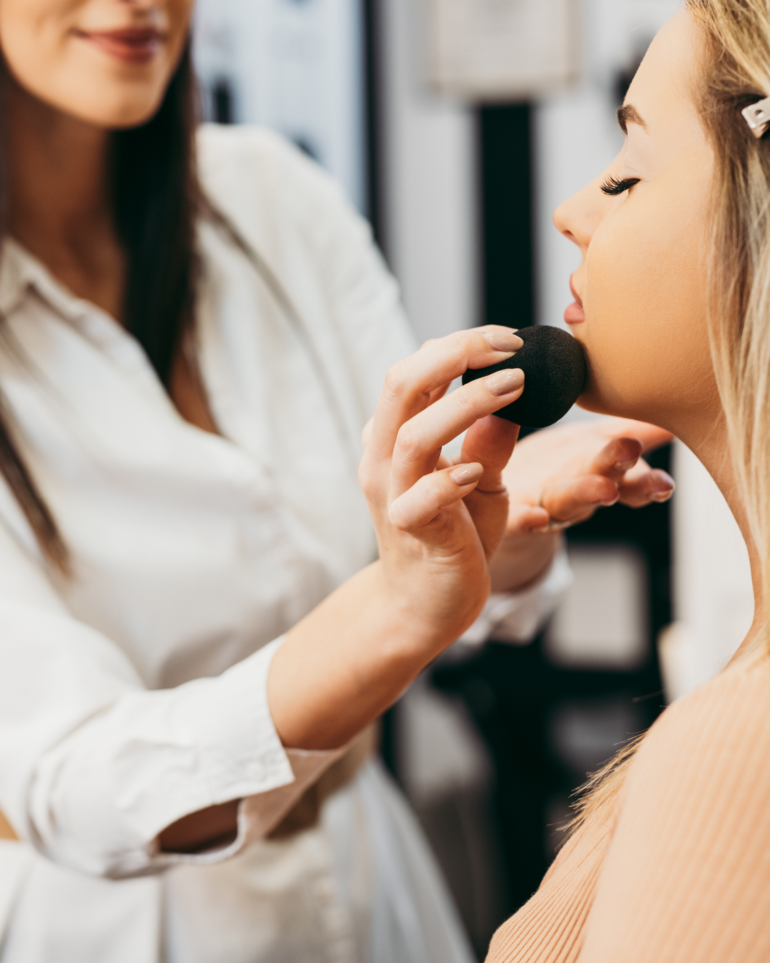 Makeup artist applying foundation to a client’s cheek in a beauty salon