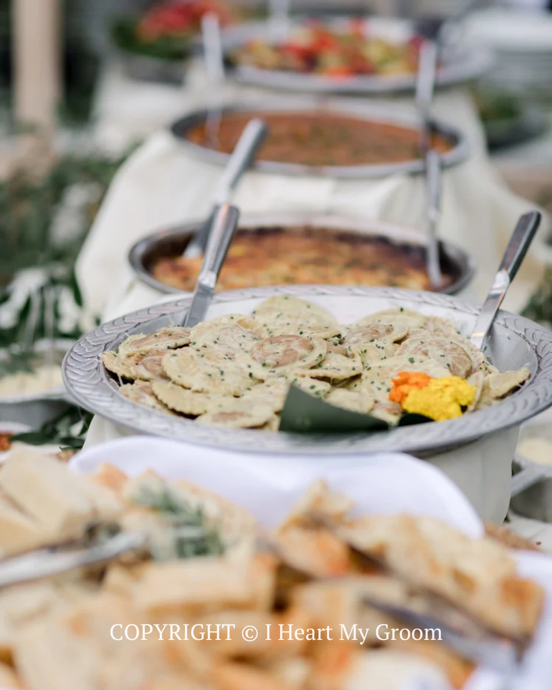 Buffet table with serving dishes of food, including flatbread and a yellow garnish, in a bright setting