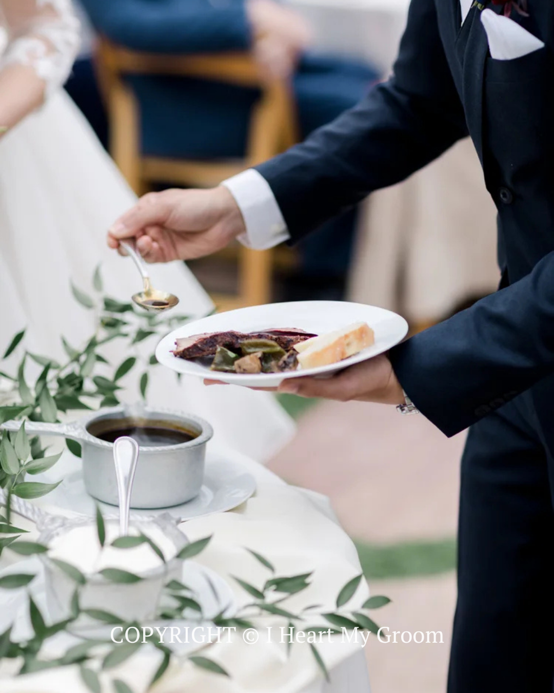 Waiter in black suit serving a plated dessert beside a cup of tea at a decorated table