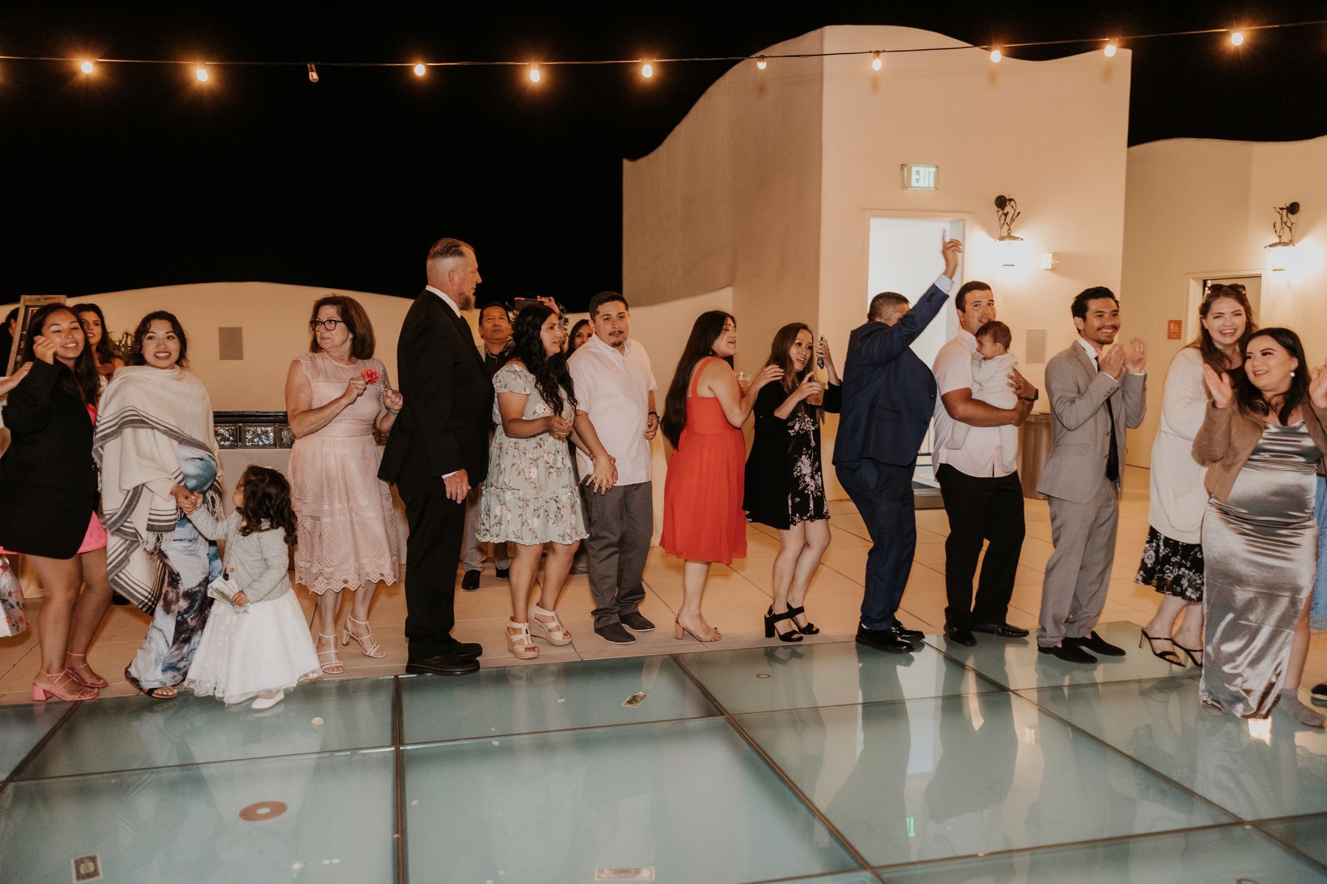 Guests dancing at an outdoor evening reception under string lights