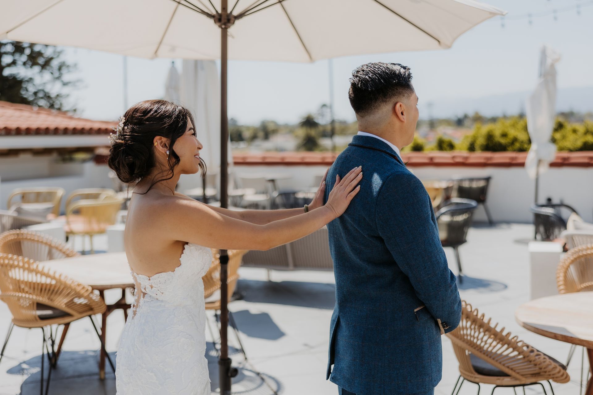 Bride touching groom’s shoulder under an umbrella at an outdoor wedding reception