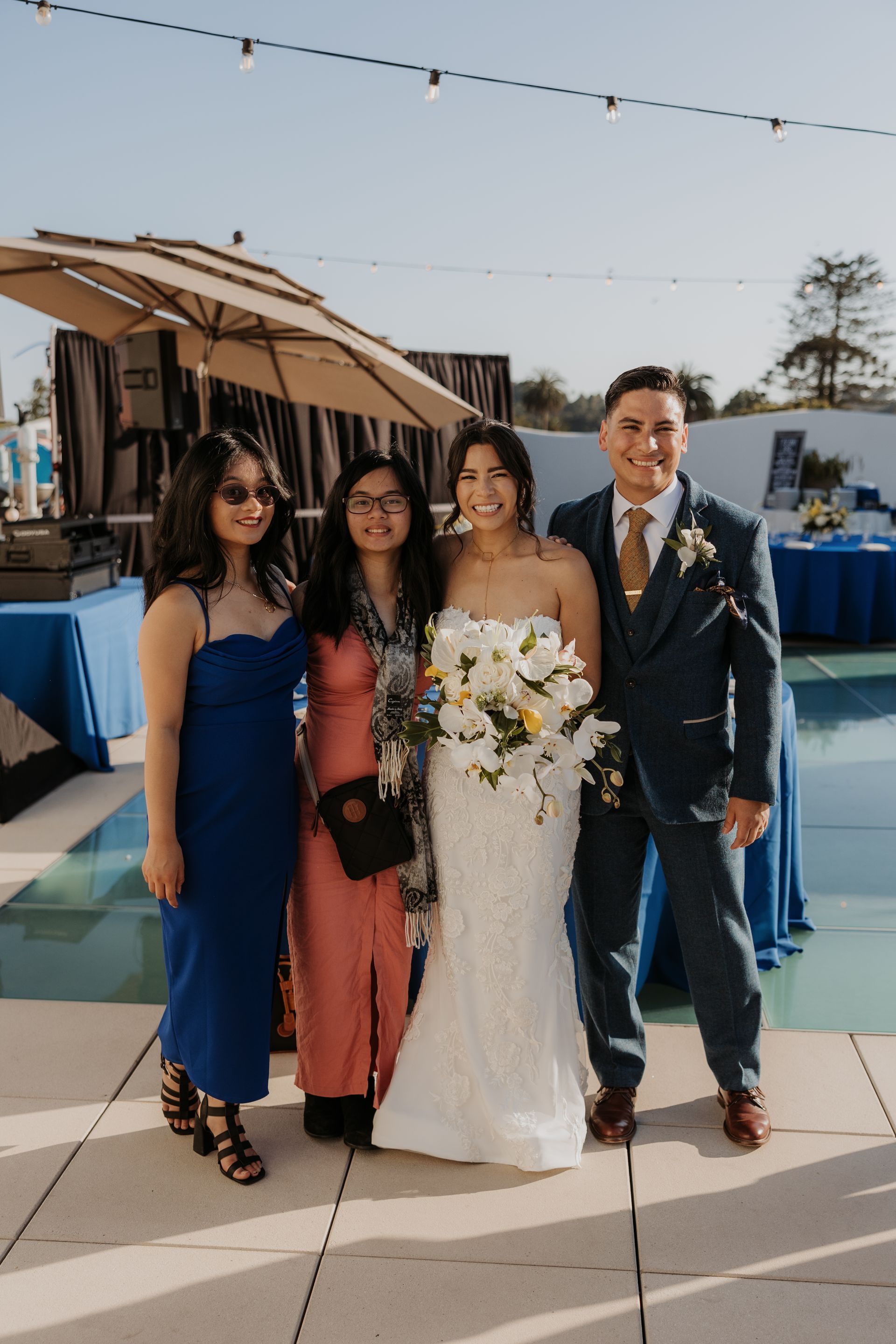Four people pose at an outdoor wedding, with the bride holding a bouquet and groom in a suit.