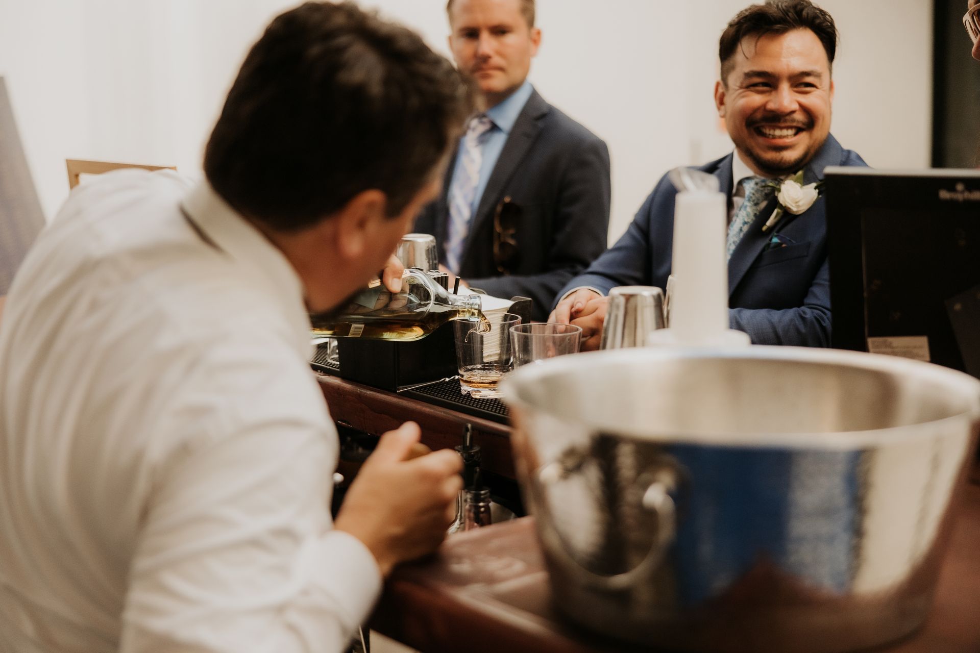 People chatting at a table in a formal indoor setting, with a metal ice bucket in the foreground.