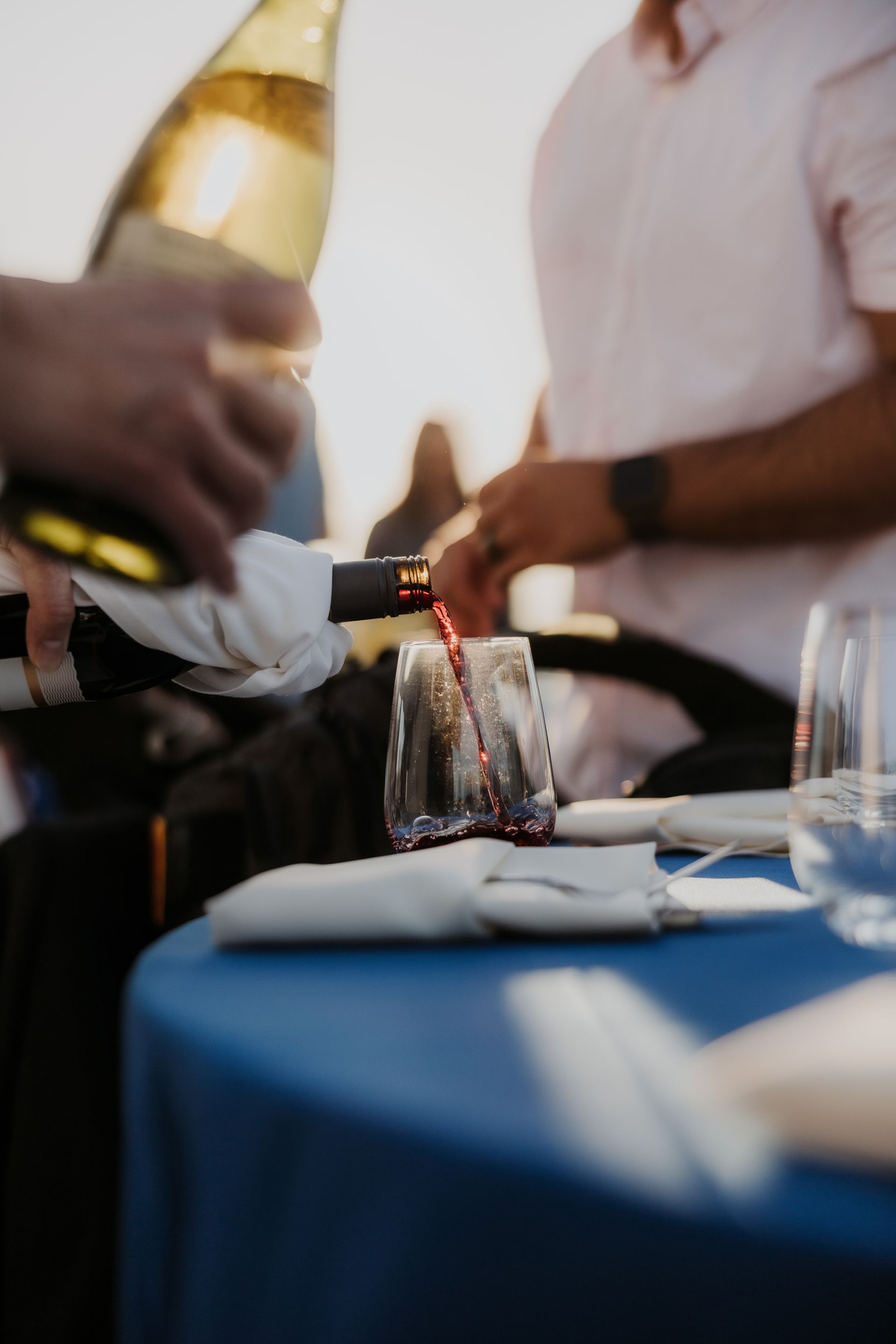 People pouring champagne into glasses at a blue-tablecloth event table