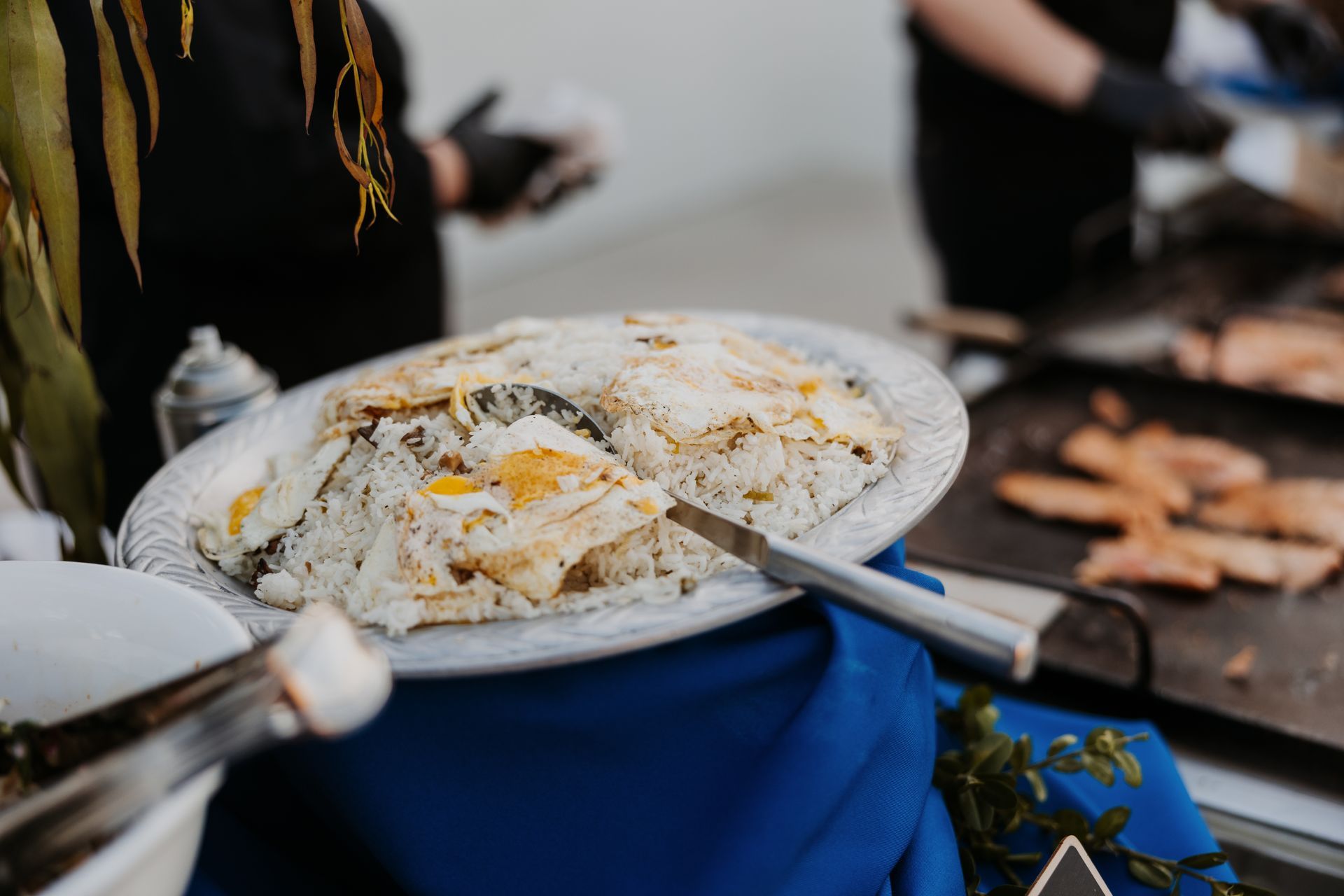 Tray of powdered pastries at an outdoor market stall with a blue tablecloth