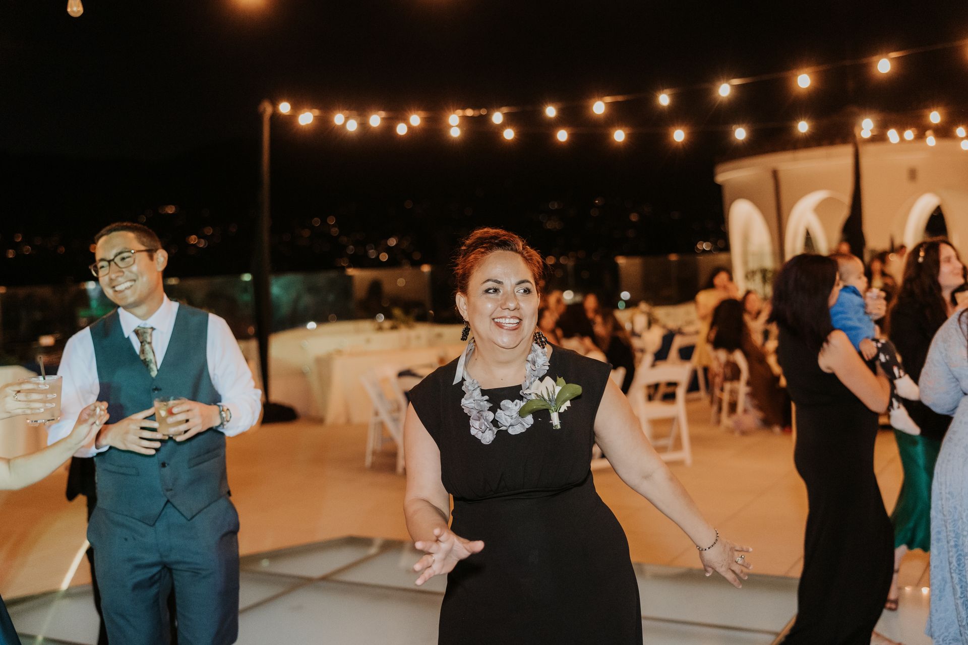 Guests dancing at an outdoor evening reception under string lights