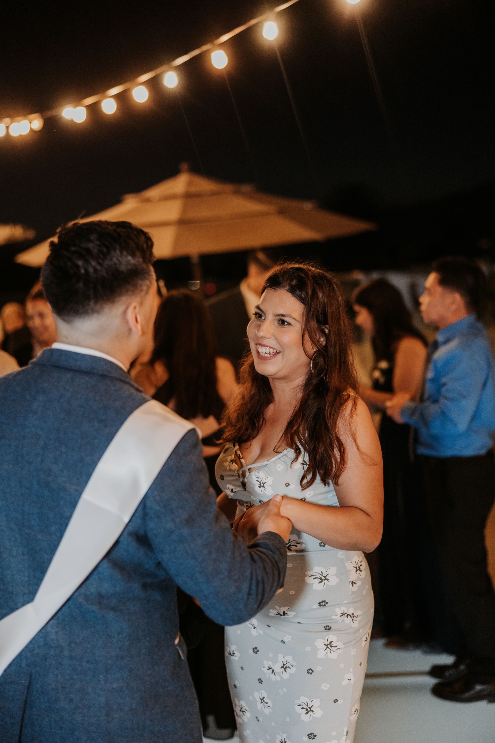 Couple dancing at an evening outdoor event under string lights