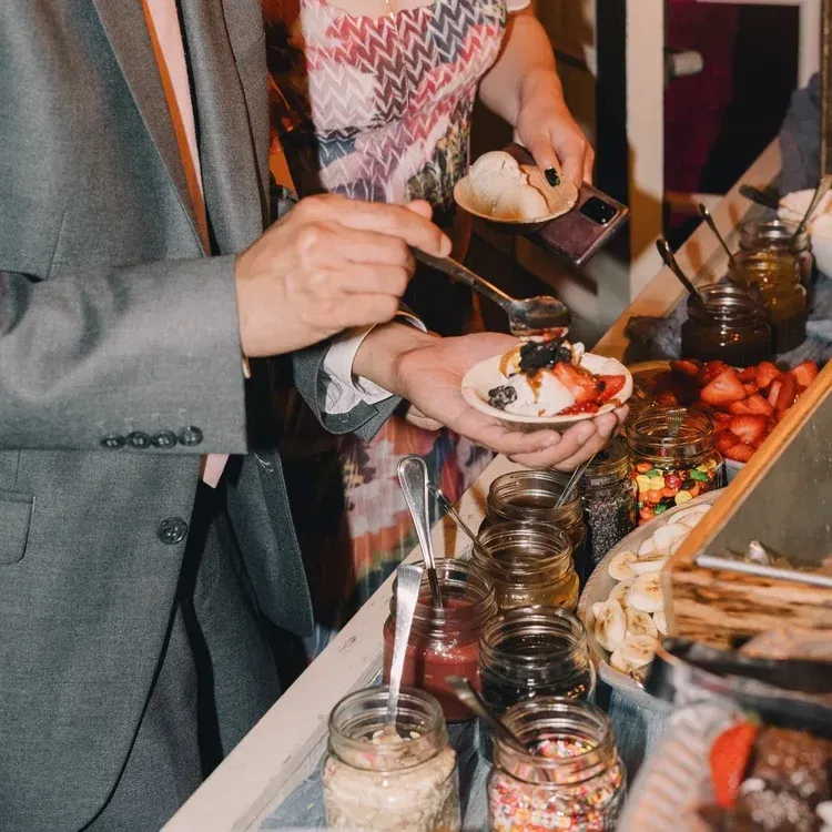 Guests serve themselves at a buffet with jars of toppings and plated food