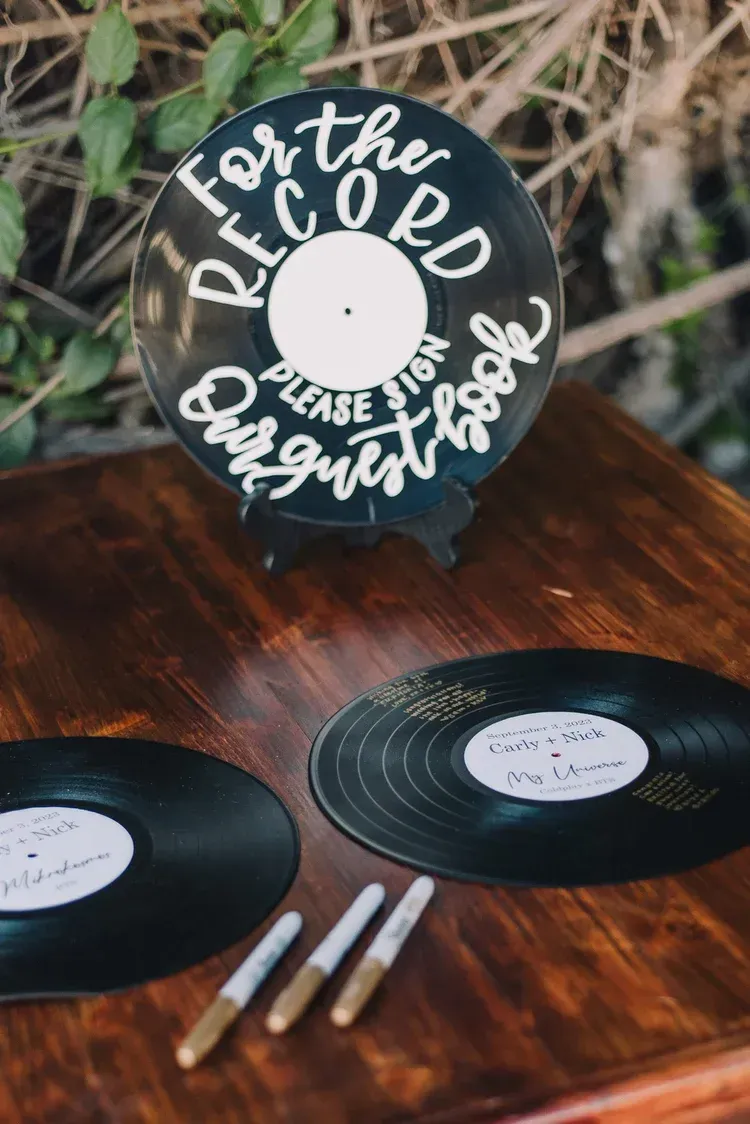 Personalized vinyl record guestbook display on a wooden table with pens and records