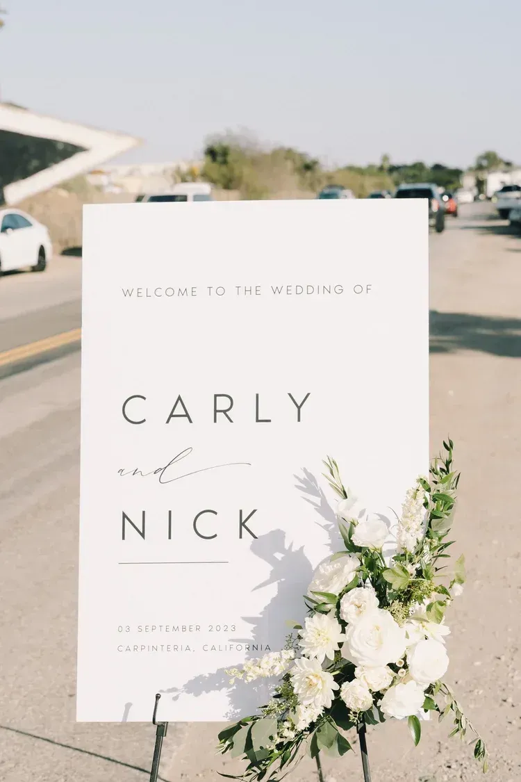 Wedding welcome sign for Carly and Nick with white floral arrangement outdoors