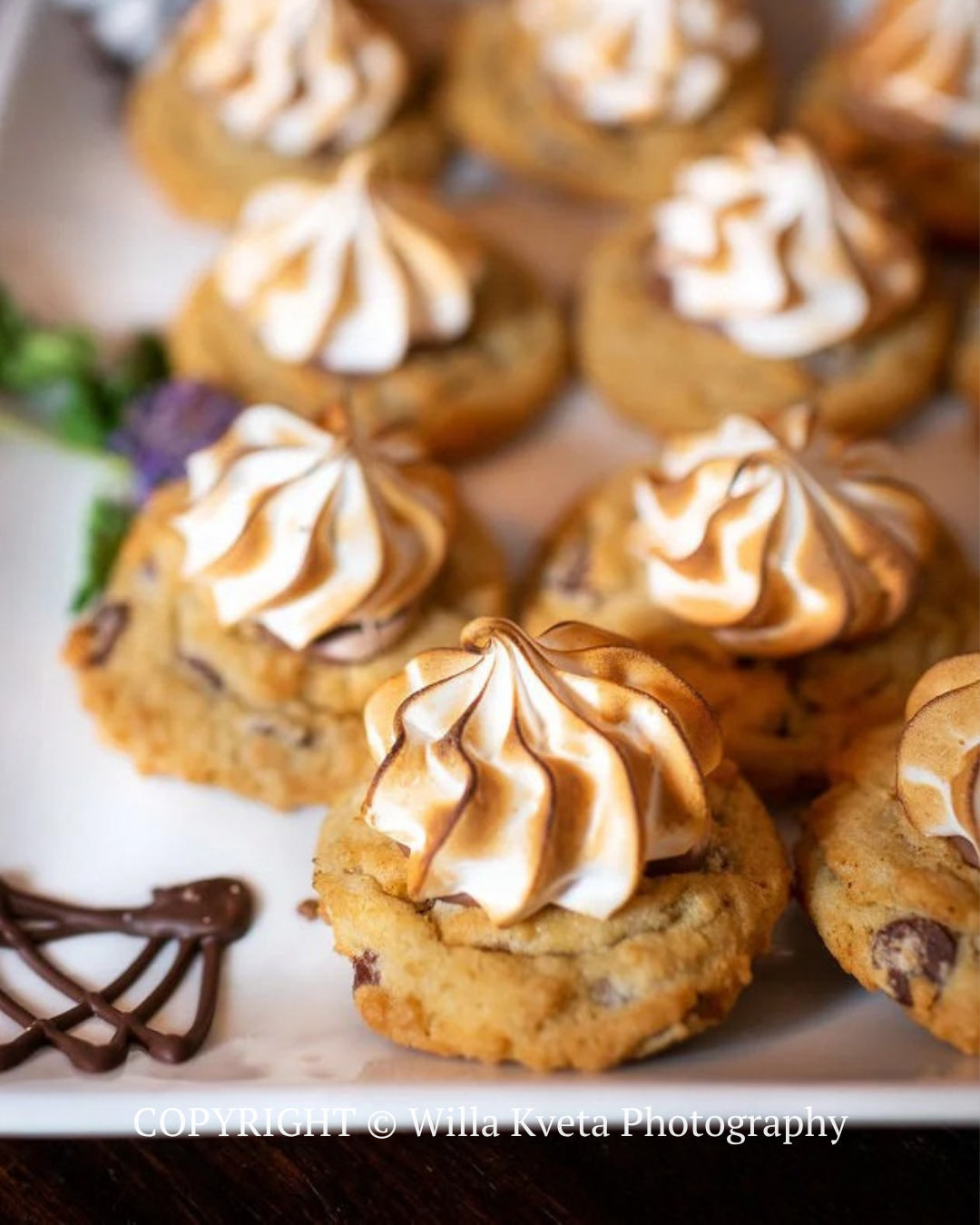 Swirled-frosted cupcakes on a white plate, with one chocolate drizzle garnish nearby